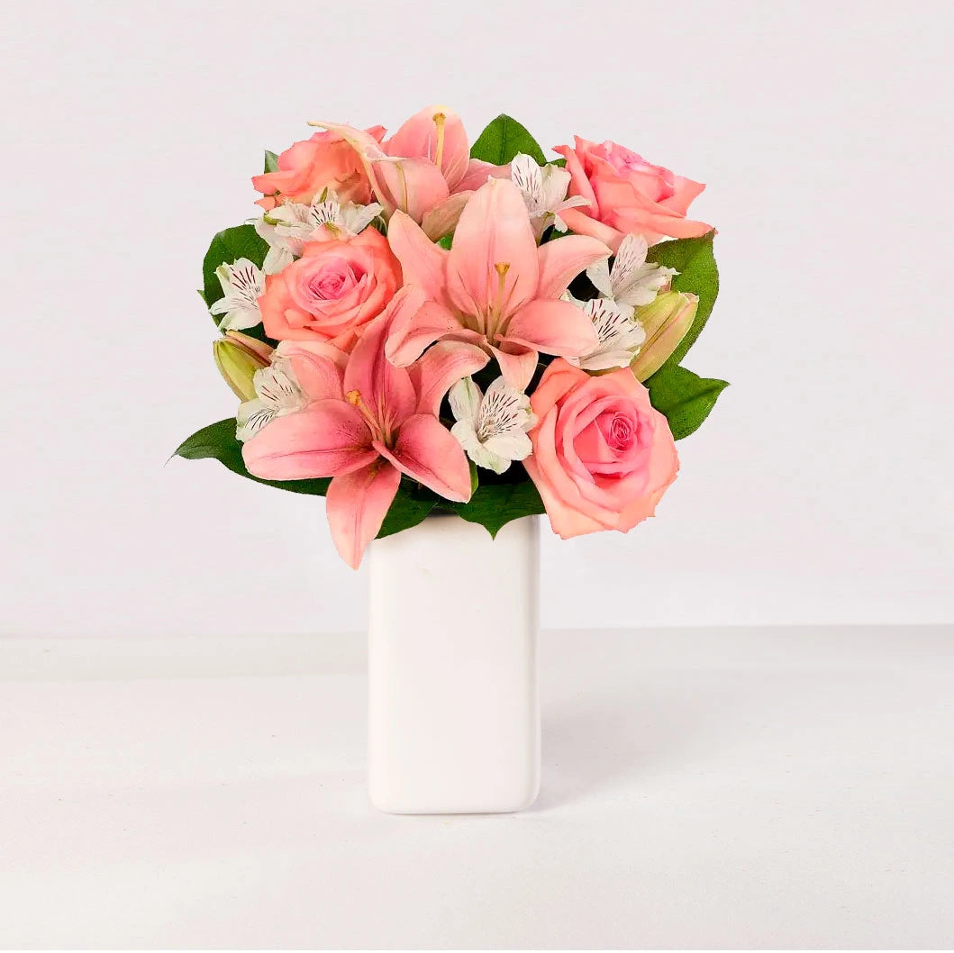 Arreglo floral de 4 rosas, 3 lirios rosados y astromelias, en un florero.