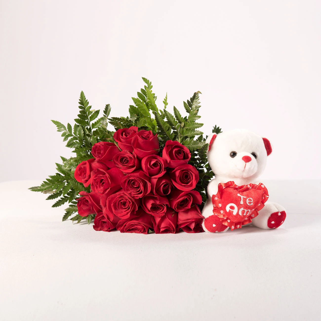 Ramo de rosas rojas acompañado de un osito de peluche.