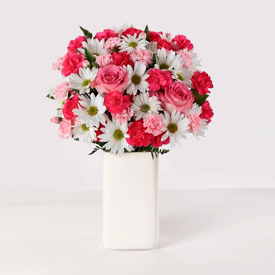 Florero con rosas rosadas, claveles rosados y margaritas blancas.