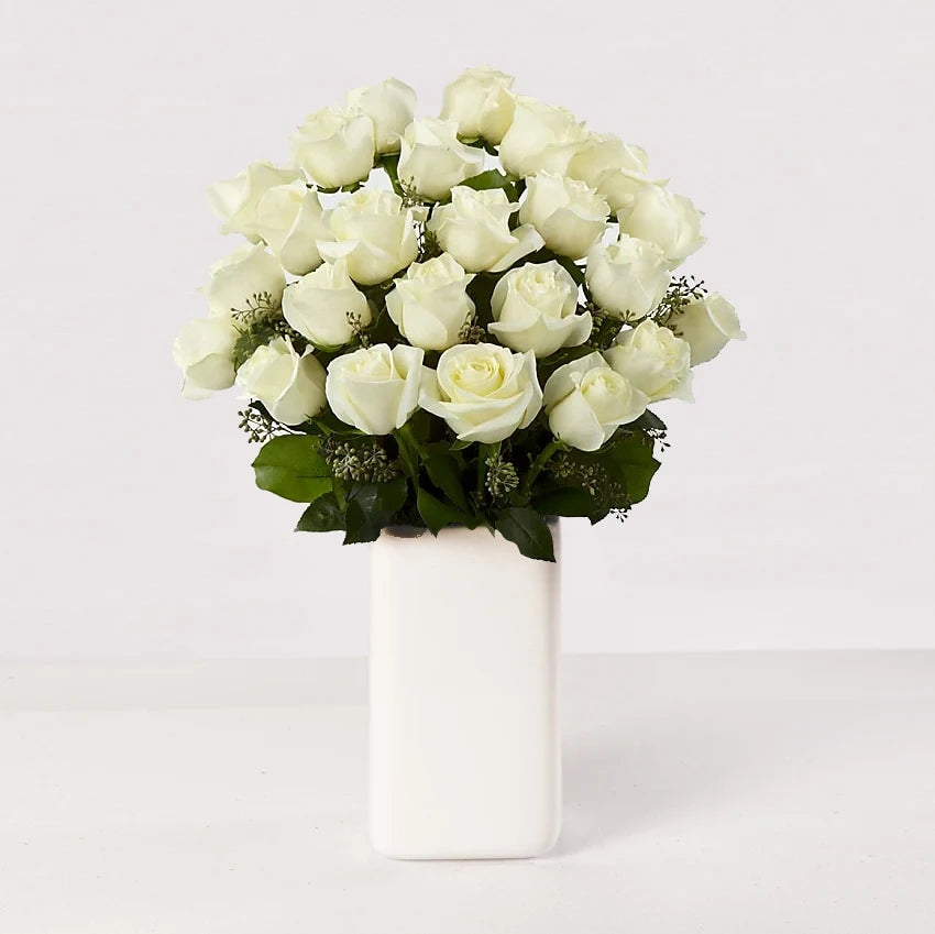 Arreglo de 24 rosas blancas sobre un florero.