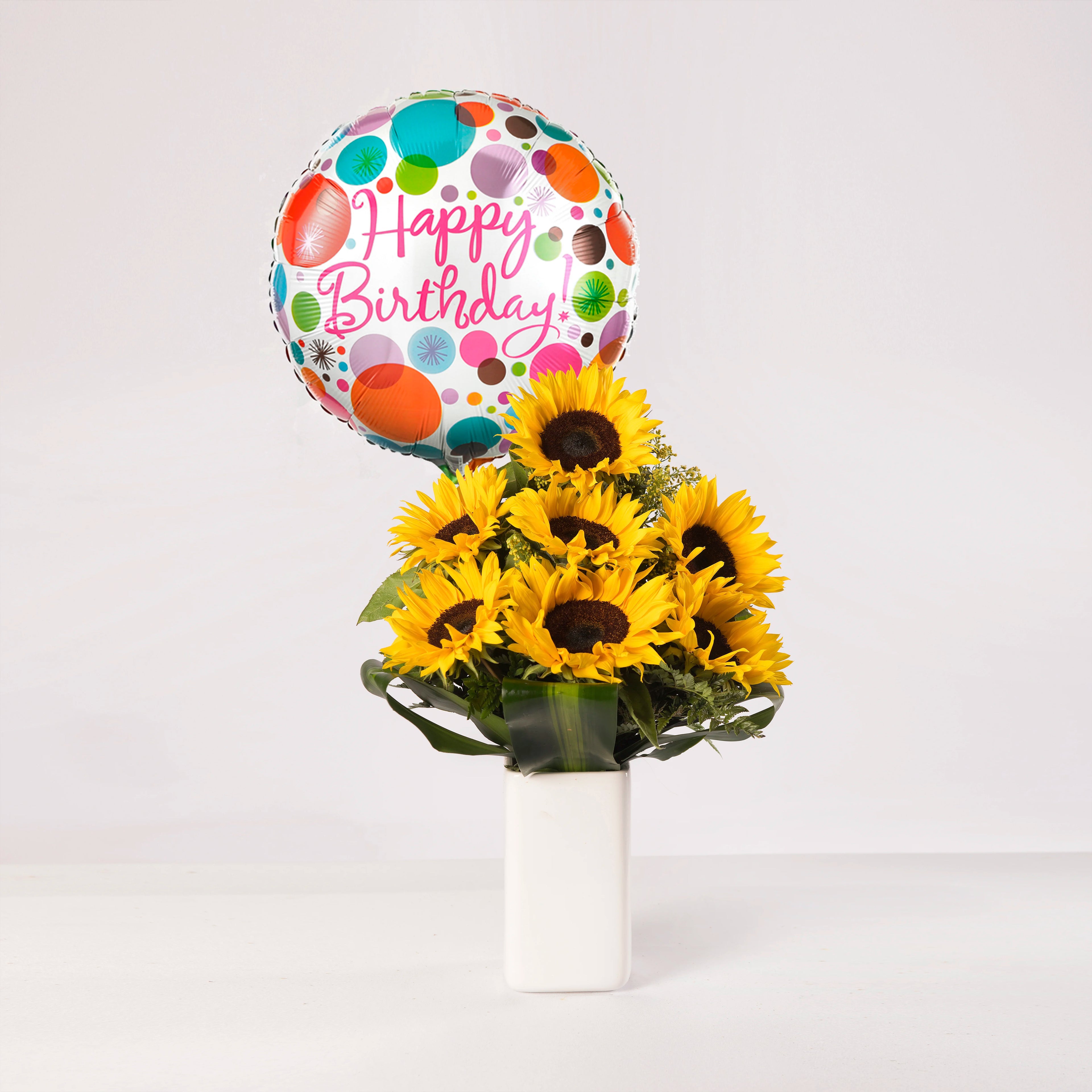 Florero con 7 girasoles, acompañado con un globo de feliz cumpleaños.