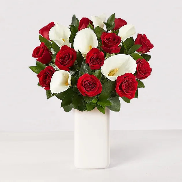 Arreglo de 12 rosas rojas acompañado de cartuchos blancos.