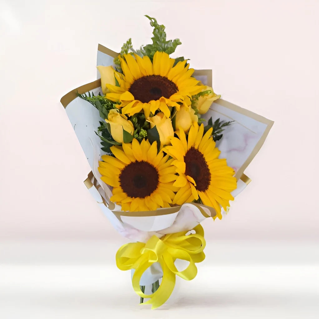 Ramo de girasoles frescos con rosas amarillas. Decorado con listón amarillo y papel decorativo blanco.