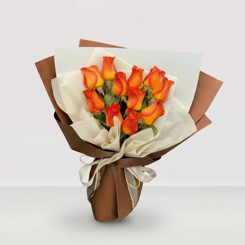 Bouquet de 12 rosas naranjas con papel blanco y café.
