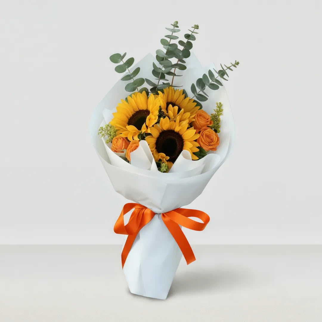 Ramo de girasoles y rosas anaranjadas con lazo naranja y papel blanco